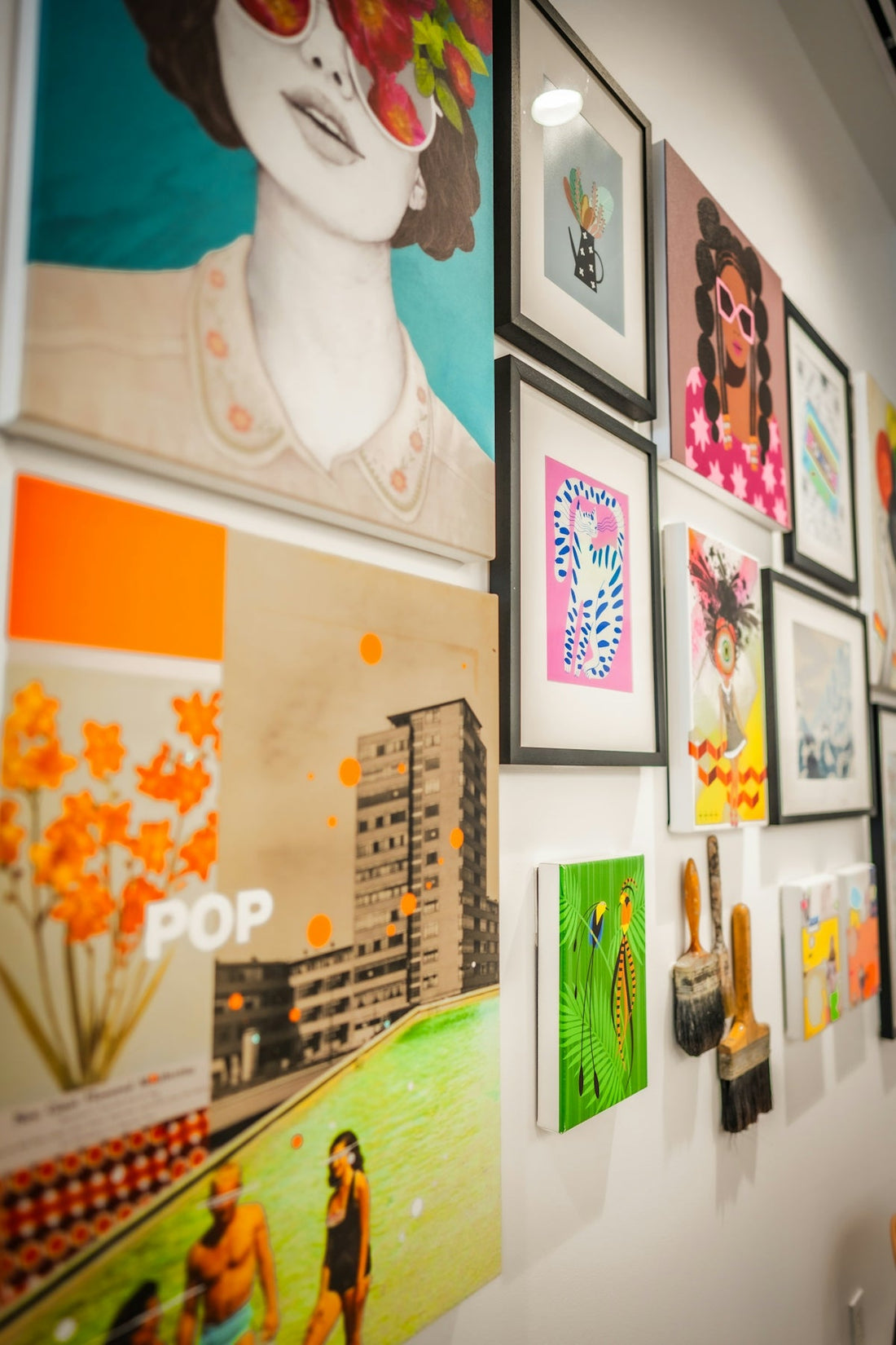 Colorful modern artworks and paintbrushes displayed on a gallery wall.